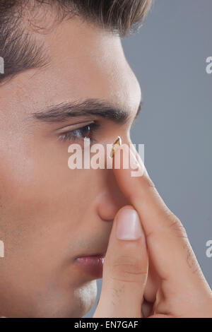 Young man putting contact lens Banque D'Images