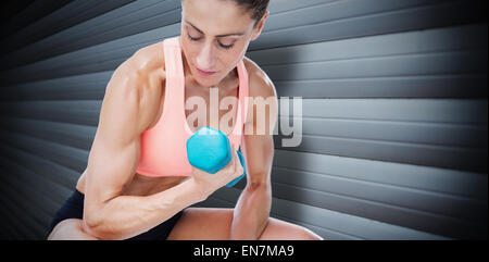 Image composite d'une femme forte de bicep faire avec haltère bleu Banque D'Images