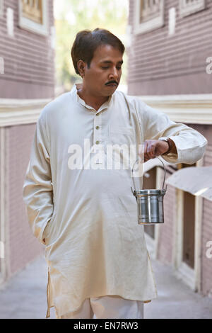 Man holding lait canister et looking at watch Banque D'Images