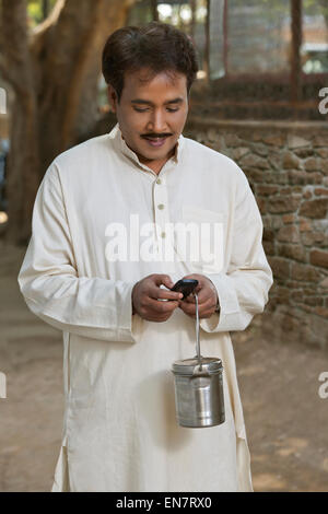 Man holding lait canister et using cell phone Banque D'Images