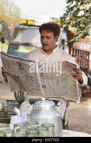 Homme lisant un journal à plateau stall Banque D'Images