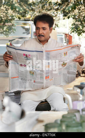 Homme lisant un journal à plateau stall Banque D'Images