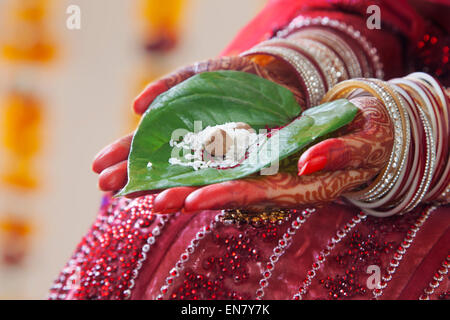 Close-up of a Brides mains effectuant des rituels de mariage avec des feuilles de riz et paan Banque D'Images