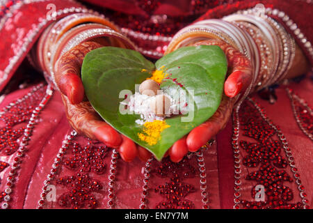 Close-up of a Brides mains effectuant des rituels de mariage avec des feuilles de riz et paan Banque D'Images