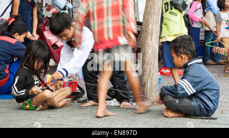 Les enfants cambodgiens ayant peu de plaisir, alors que vendre des bracelets à l'étrangers dans la rue à Phnom Penh, Cambodge. Banque D'Images