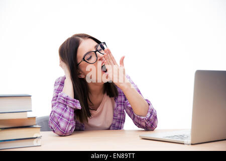 Jeune femme assise à la table et le bâillement sur fond blanc Banque D'Images