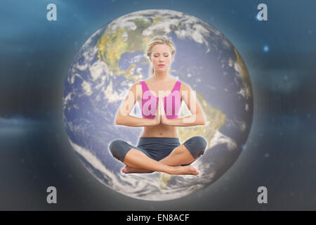 Image composite de calm blonde sitting in lotus pose avec les mains Banque D'Images