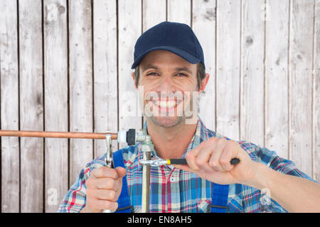 Image composite de portrait of happy plumber fixing pipe Banque D'Images