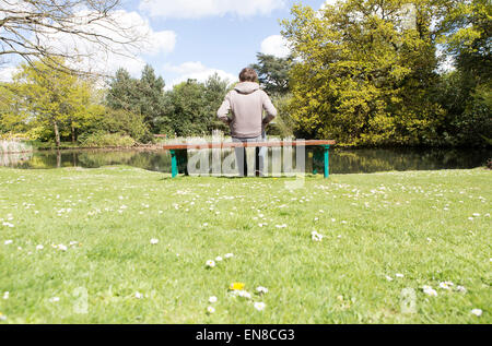 Un homme est assis seul sur un banc de parc Banque D'Images