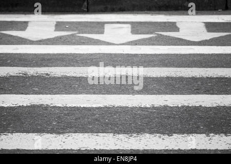 Trois flèches blanches et des lignes sur la route d'asphalte de couleur gris foncé, passage pour piétons, signalisation Banque D'Images