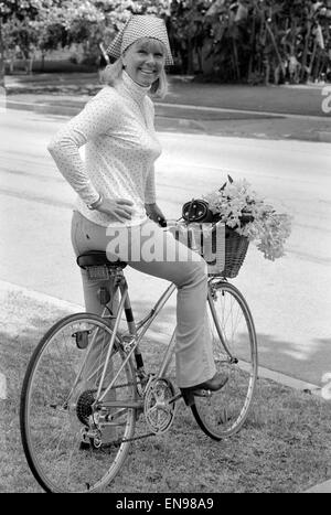 Doris Day vu tenant un bouquet de fleurs sur sa bicyclette, elle roule tous les jours pour garder la forme. 26 août 1980. Banque D'Images