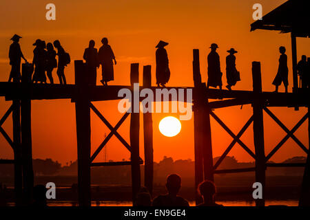 Les personnes qui traversent le pont en bois au coucher du soleil, U Bein bridge, Mandalay, Myanmar. Banque D'Images