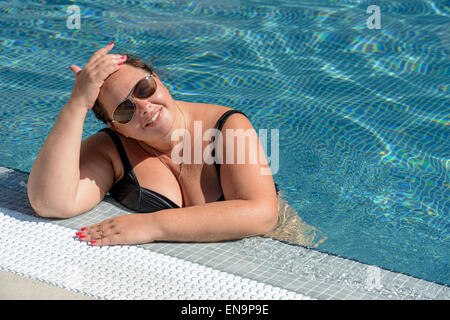 Portrait of mid adult woman dodu dans l'eau bleue au bord de piscine. Banque D'Images