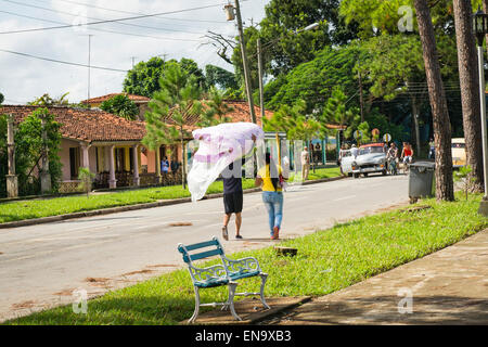 Vinales Cuba rue principale avenue road shopping femmes deux matelas rose tête de vieilles voitures américaines banc maisons arbres herbe Banque D'Images