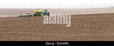 Machines agricoles dans le domaine de l'engrais en granules, et propager les semis du blé, sur une journée de printemps venteux dans les champs agricoles fertiles de l'Idaho. Banque D'Images