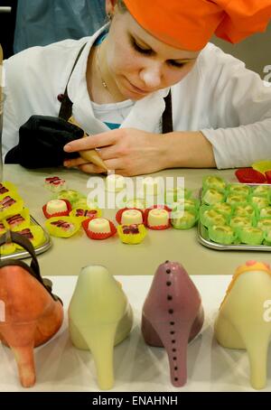 Oldisleben, Allemagne. 10 avr, 2015. Confectionist maître, Juliane Siedler, mots sur les pralines et les hauts talons dans la zone d'affichage du doigt Karin Goethe Chocolaterie à Oldisleben, Allemagne, 10 avril 2015. Les chaussures à talons hauts en couleurs font partie de la vaste et de grande qualité production praline dans son entreprise, qui a été fondée il y a dix ans. Photo : WALTRAUD GRUBITZSCH/dpa/Alamy Live News Banque D'Images