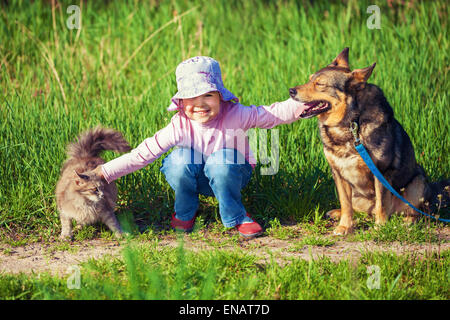 Happy little girl Playing with dog et cat en plein air Banque D'Images