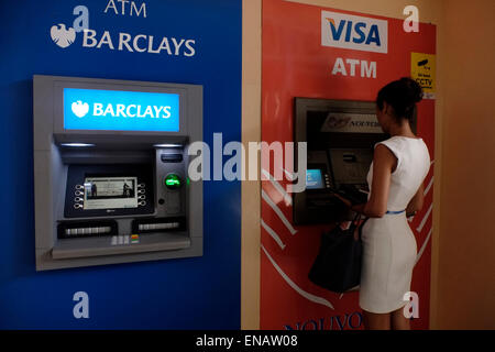 Une jeune femme prend de l'argent dans un distributeur automatique de billets à l'aéroport de Victoria, dans les îles Seychelles Banque D'Images