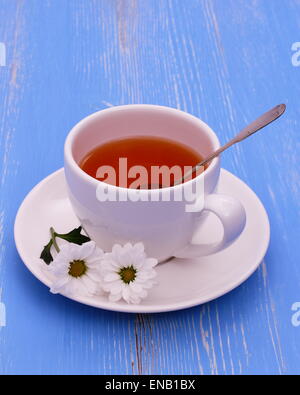 Tasse de thé blanc et de fleurs sur fond de bois bleu, vertical Banque D'Images