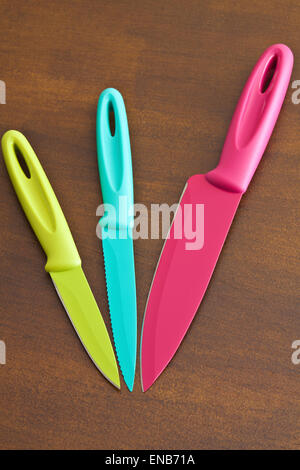Ensemble de grands et petits couteaux de cuisine dentelée couleur sur une planche en bois Banque D'Images