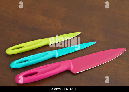 Ensemble de grands et petits couteaux de cuisine dentelée couleur sur une planche en bois Banque D'Images