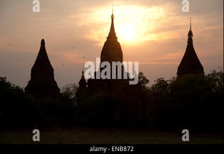 Trois silhouettes sombres des flèches contre le temple d'or d'un coucher de Bagan Myanmar Banque D'Images