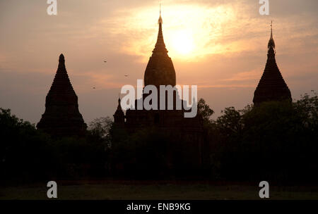 Trois silhouettes sombres des flèches contre le temple d'or d'un coucher de Bagan Myanmar Banque D'Images