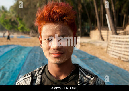 Portrait d'un jeune pêcheur birman funky avec les cheveux teints en bleu sur la plage de Ngapali avec filets de pêche derrière lui Banque D'Images