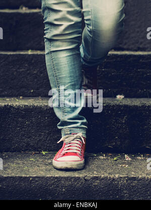 Little girl in red sneakers et jeans faire premier pas dans l'escalier Banque D'Images