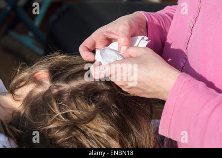 Mère à la recherche de poux de tête à sa petite fille à la lumière du soleil Banque D'Images