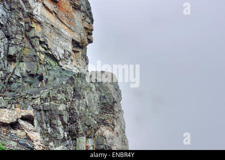 Female hiker sur une pente raide sentier alpin dans un épais brouillard, side view Banque D'Images