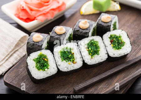 Rouleaux de sushi avec salade chuka sur une planche en bois Banque D'Images