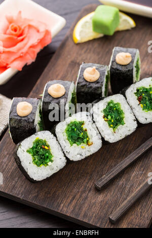 Rouleaux de sushi avec salade chuka sur une planche en bois Banque D'Images