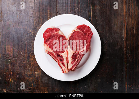 Forme de coeur la viande crue Ribeye Steak entrecote on white plate Banque D'Images