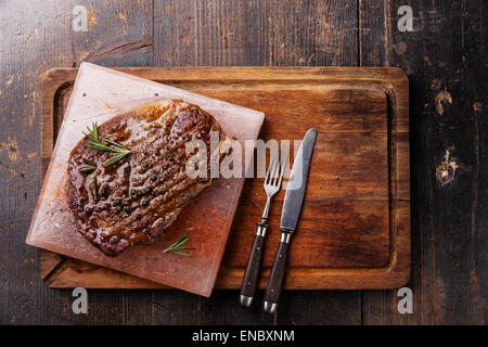 Black Angus Steak grillé sur Faux-sel rose de l'himalaya bloc sur fond de bois foncé Banque D'Images