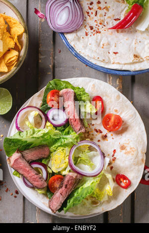 Vue aérienne sur le dîner de style mexicain avec des tacos, des légumes, des nachos chips et guakomole, servie sur table en bois gris. Banque D'Images