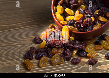 Les raisins secs dans un plat sur une table en bois brun Banque D'Images