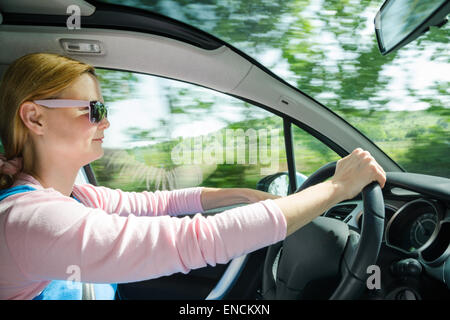 Smiling Beautiful woman in sunglasses roulant à vitesse élevée voiture avec pare-brise panoramique. Photo interne à faible vitesse d'obturation Banque D'Images