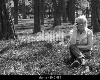 1er mai 2015 - Portrait of middle-aged woman assis sur la pelouse dans le parc et à parler au téléphone © Igor Golovniov/ZUMA/ZUMAPRESS.com/Alamy fil Live News Banque D'Images