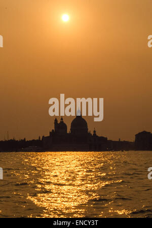 Venise, Province de Venise, Italie. Apr 30, 2015. Le soleil se couche derrière la célèbre 17e siècle dôme baroque de Santa Maria della Salute, une église catholique et basilique, emblématique de la ville de Venise et sa ligne d'horizon, debout sur l'étroit doigt de Punta della Dogana, entre le Grand Canal et le Canal de la Giudecca, à le bassin de St Marc (Bacino di San Marco). Venise est l'un des plus populaires destinations touristiques internationales. © Arnold Drapkin/ZUMA/Alamy Fil Live News Banque D'Images