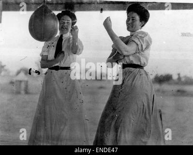 Deux femmes s'entraînent avec un sac de vitesse, démontrant leur athlétisme et leur entraînement dans un cadre de boxe ou d'arts martiaux, mettant l'accent sur le développement de la force et de la dextérité. Banque D'Images