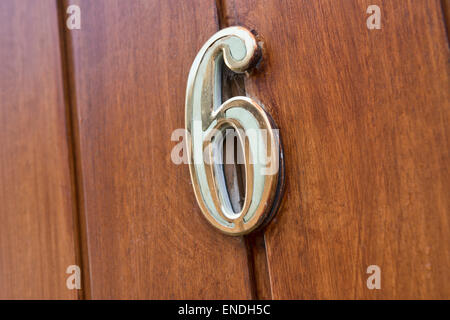 La chambre numéro 6 faits de laiton peint en vert, montée au dessus d'un trou de sécurité spy sur une porte en bois Banque D'Images