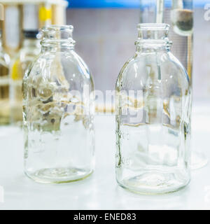 Bouteilles en verre vide sur la table. Verrerie de laboratoire de recherche Banque D'Images