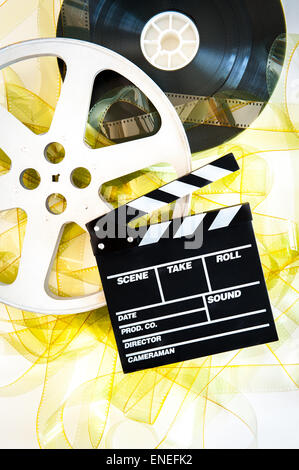 Movie clapper sur bobines 35 mm pellicule jaune déroulé sur fond blanc à la verticale Banque D'Images