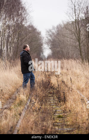 Homme d'âge moyen est de marcher le long des voies de chemin de fer abandonnée Banque D'Images