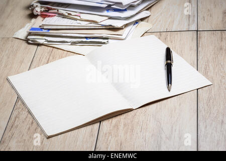 Dans l'image un cahier avec des feuilles blanches et un stylo avec des lettres en arrière-plan. Banque D'Images