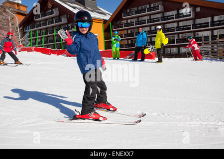 Jeune garçon apprendre le ski en face de chalets de vacances Banque D'Images