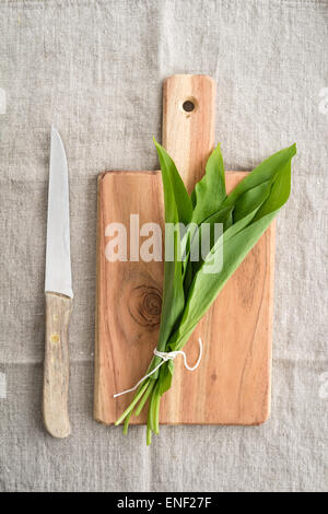 L'ail sauvage frais feuilles sur planche à découper en bois avec couteau sur lin naturel Banque D'Images