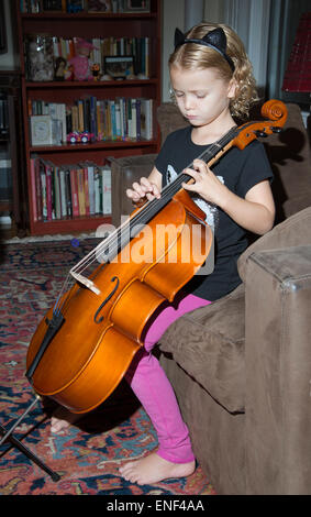 Petite fille jouant un violoncelle pinçant les cordes avec ses doigts Banque D'Images