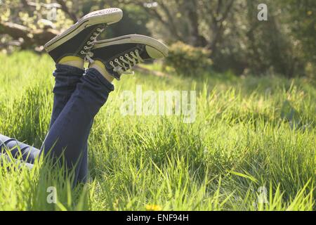 Jambes allongé dans l'herbe dans un parc sur sunny day Banque D'Images